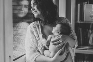 A tender black and white portrait of a mother cradling her baby in a joyful embrace.