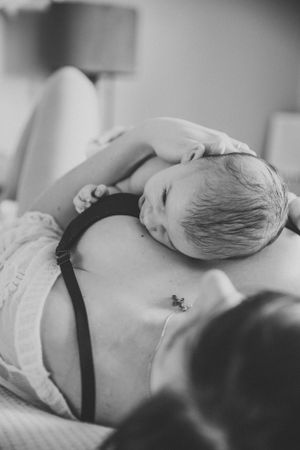 A sleeping infant rests peacefully on a reclining figure with a small tattoo visible.