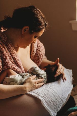 An intimate nursing moment captured in warm tones as baby feeds peacefully.