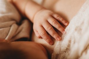 Close-up of a tiny baby's hand resting gently against soft fabric.
