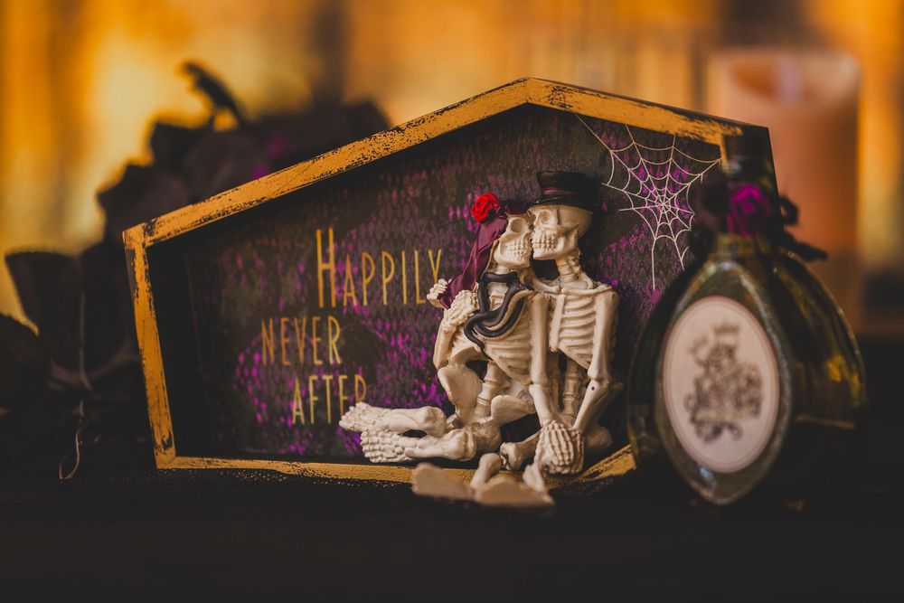 Halloween skeleton couple figurines in a coffin box with Happily Never After text and spider web decoration.