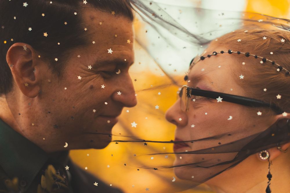 Romantic couple gazing at each other under a star-patterned veil at their wedding ceremony.