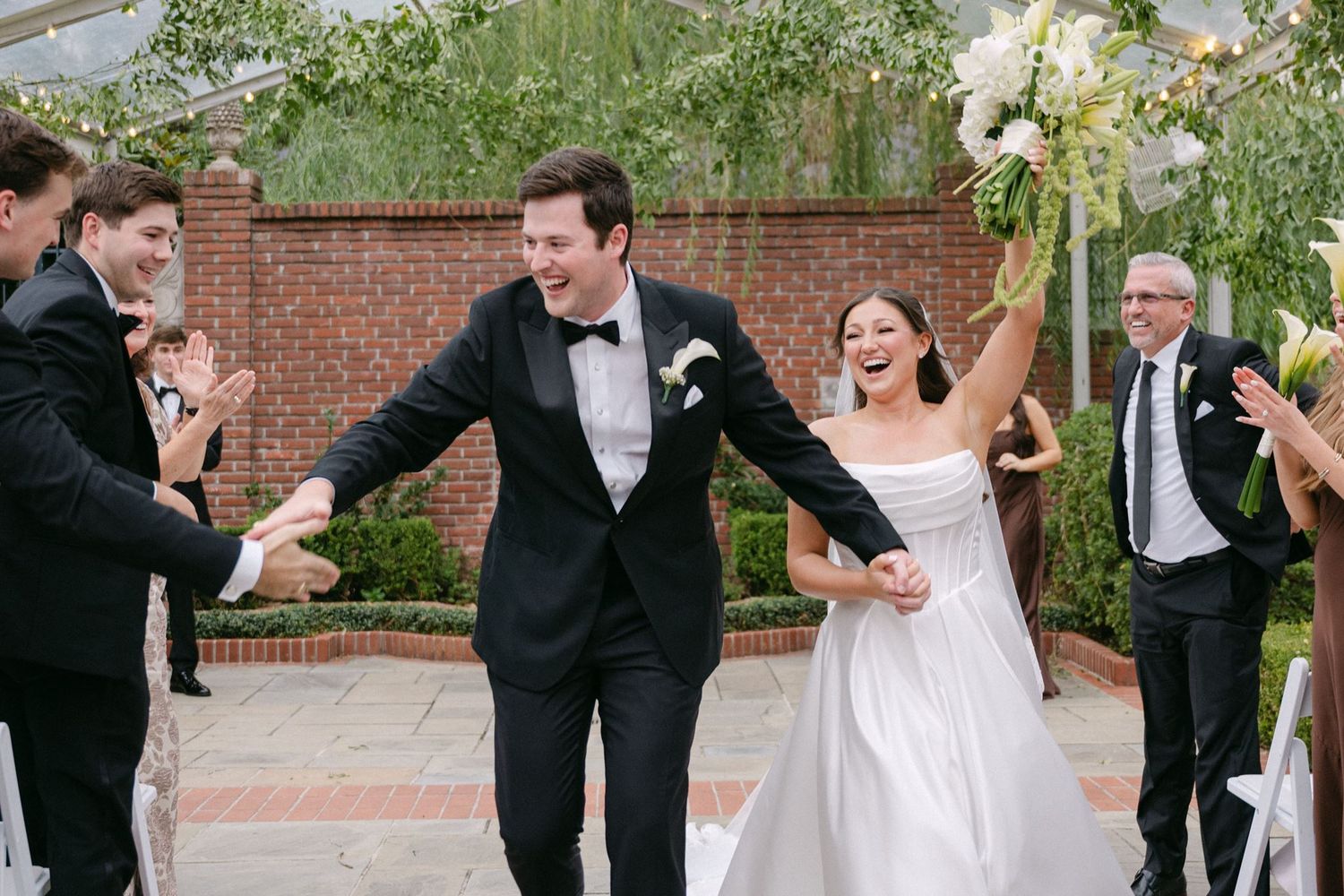 Bride and groom cheering as they walk up the aisle.
