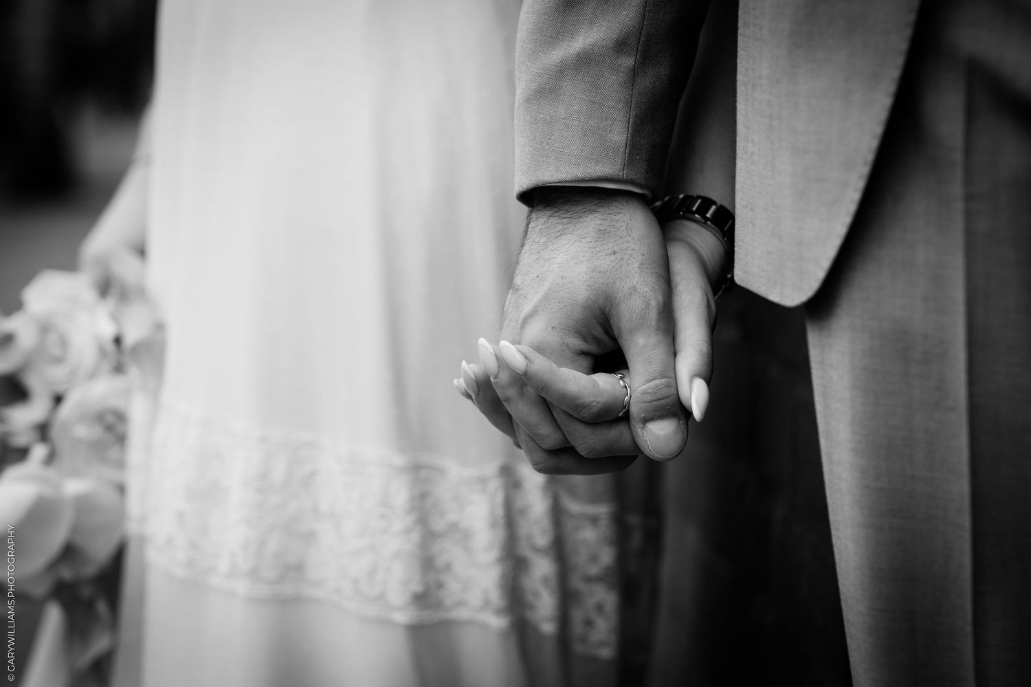 Black and white photo of a bride and groom holding hands at their wedding ceremony.