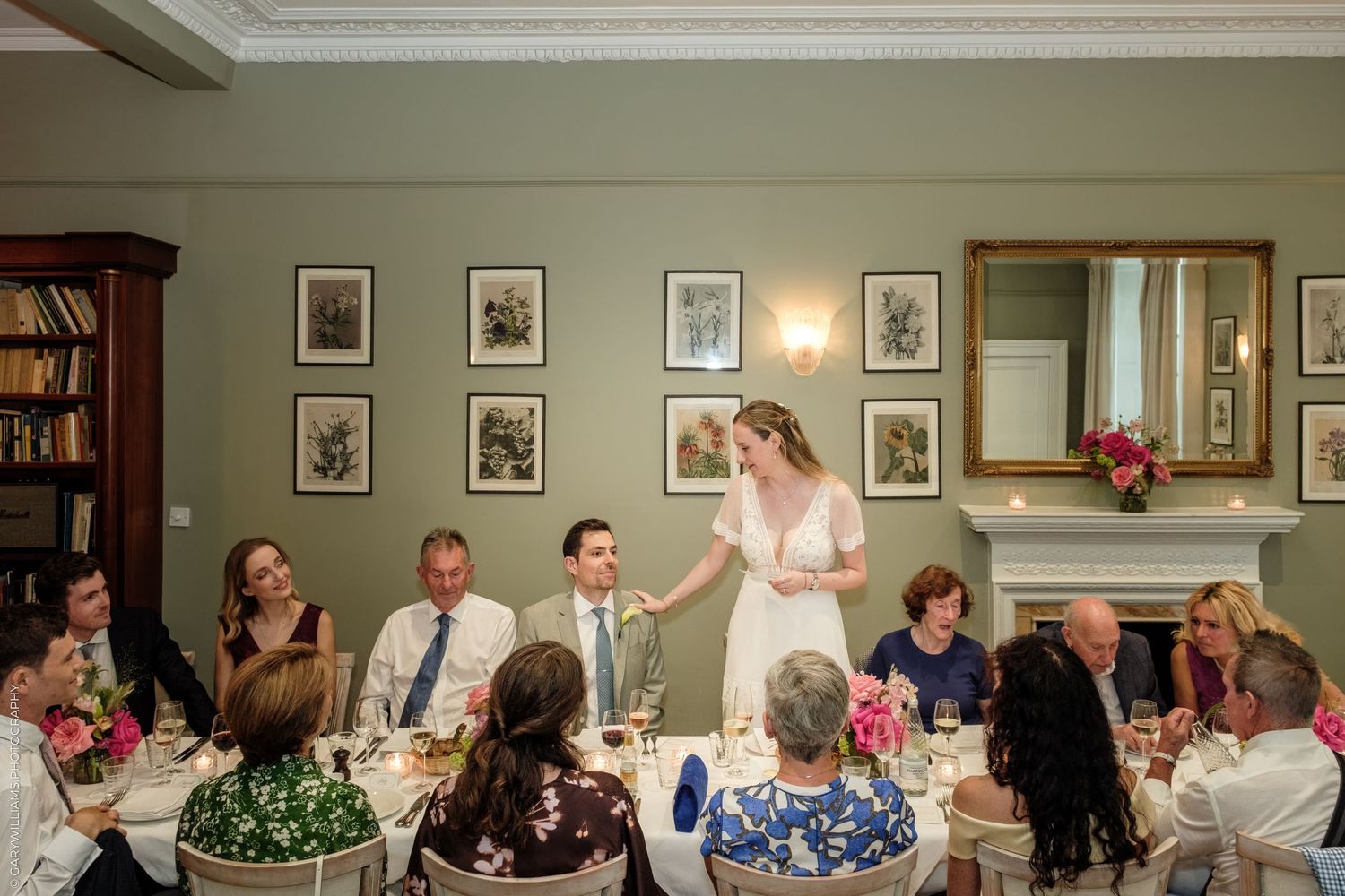 Bride and groom sharing a toast with guests at elegant wedding reception dinner in a classic decorated room.