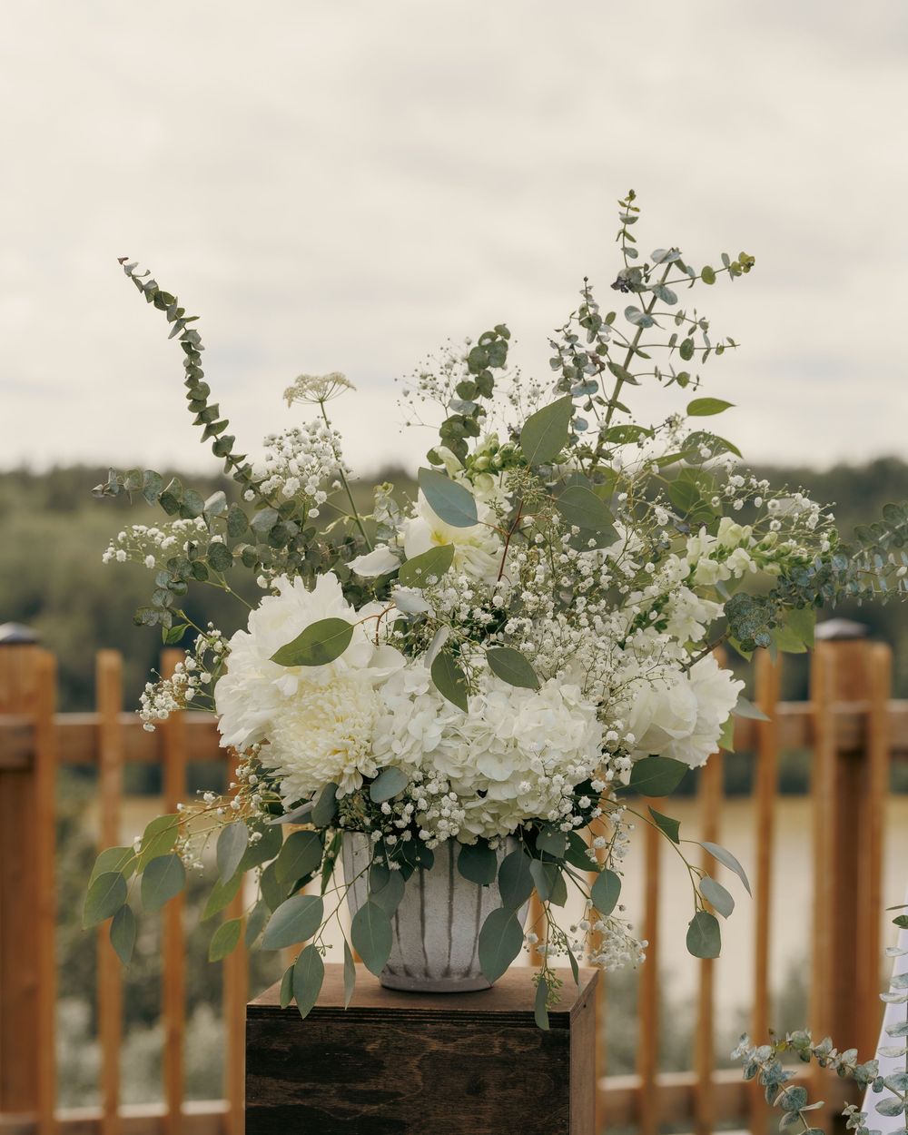 Lush white hydrangea and eucalyptus floral arrangement in a white vase for a wedding ceremony.