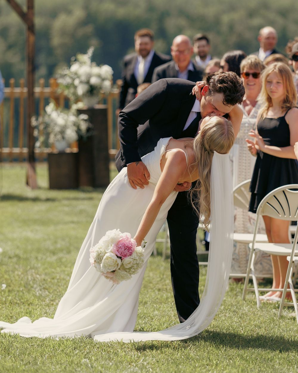 Groom dips bride for a romantic kiss while walking back down the aisle after ceremony.