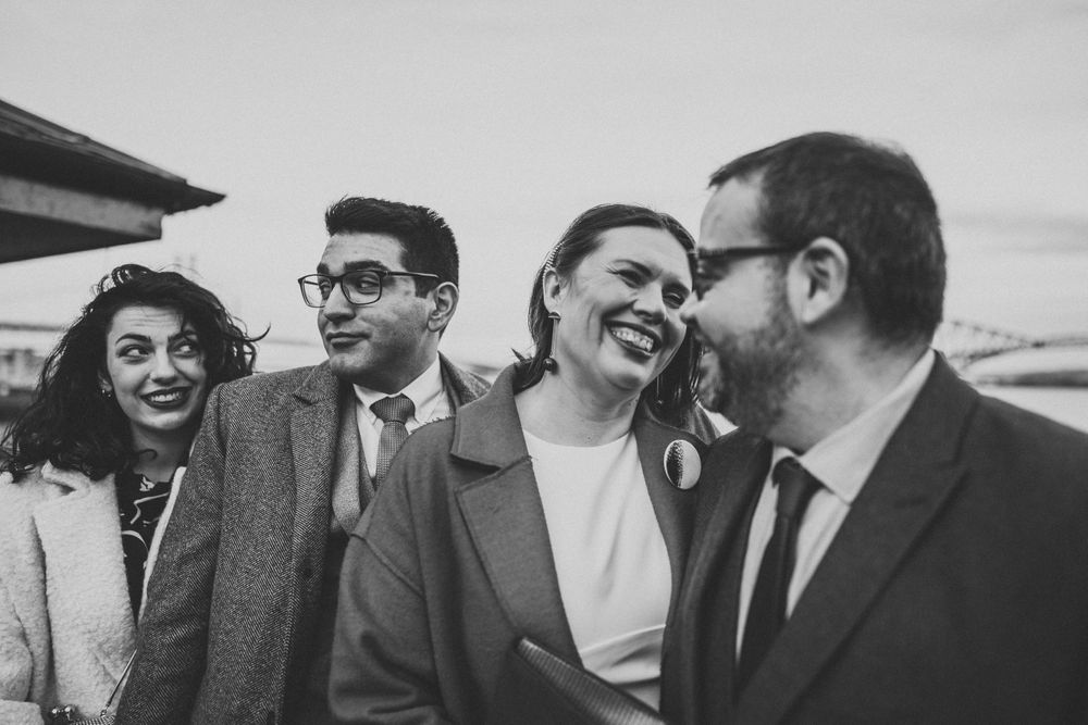 Black and white portrait of four people laughing together outdoors.