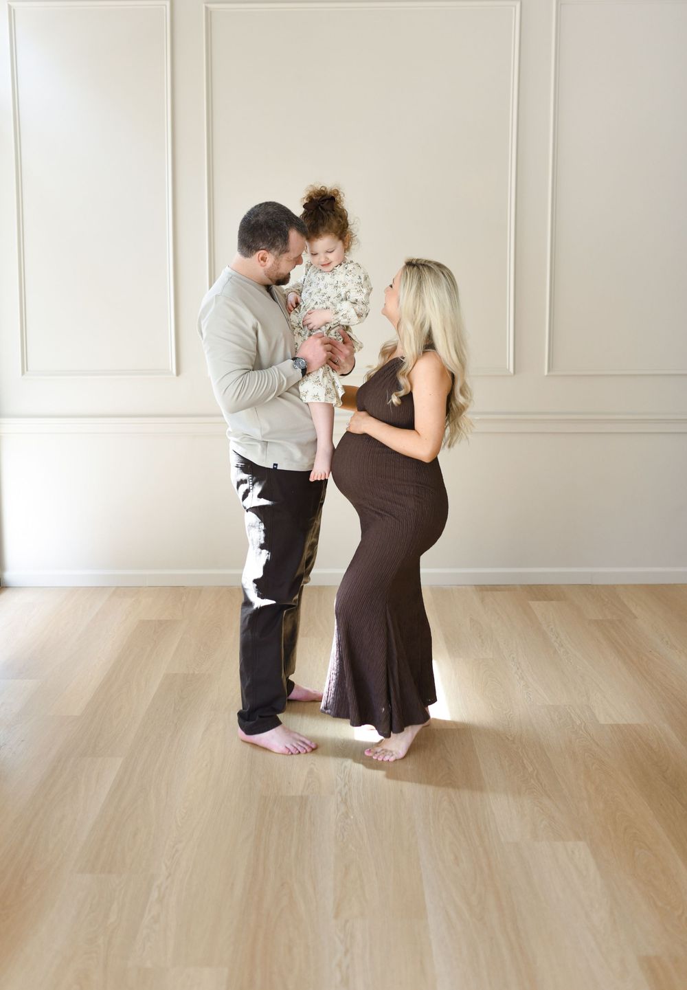 A family of three during a maternity session in a natural light studio.