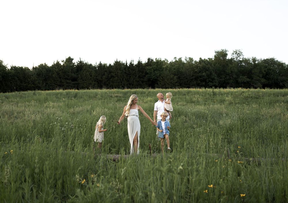 A family during a maternity session outdoors in a green field.