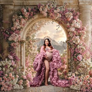 Sydney maternity photographer: mother stands in romantic floral arch scene wearing gold flower crown and tulle couture robe, smiling.