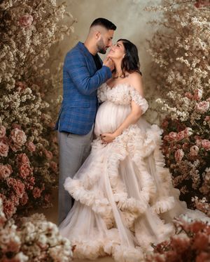 Timeless maternity: woman in dreamy soft tulle gown and parter stand in romantic floral digital scene.