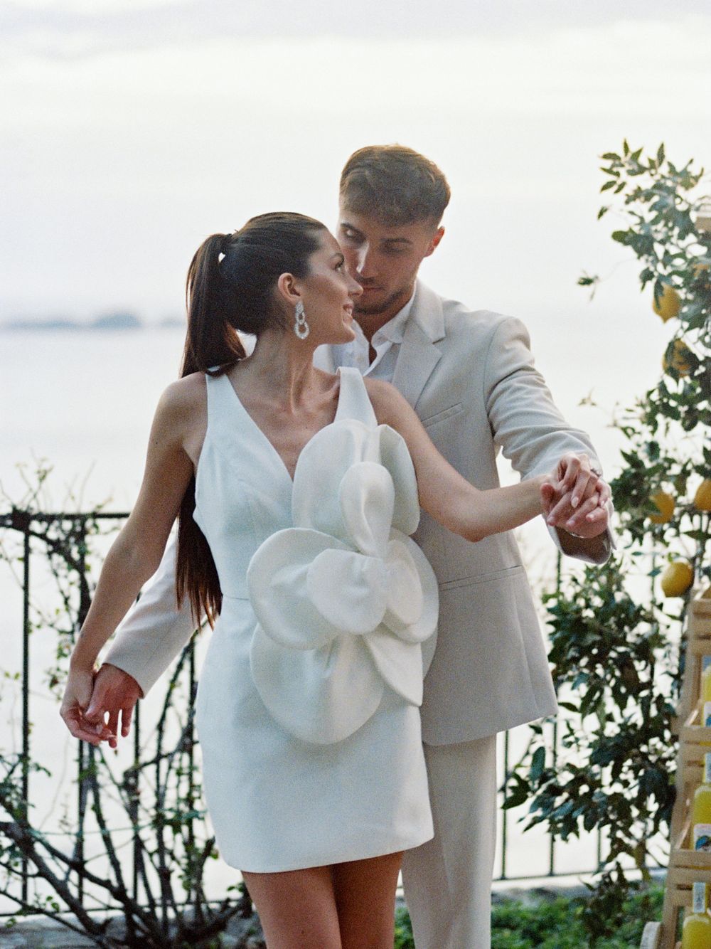 Romantic couple dancing together on an outdoor terrace overlooking a scenic waterfront view.