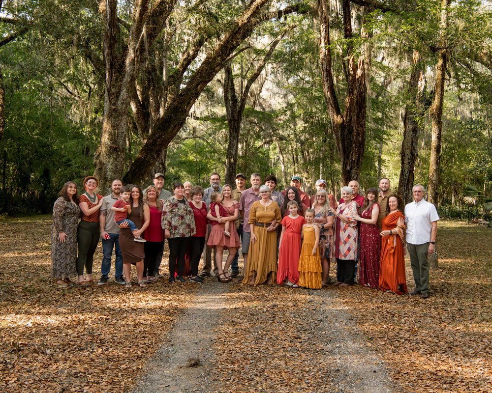 Large extended family portrait beneath oak trees in Tampa, Florida, capturing multiple generations together outdoors.