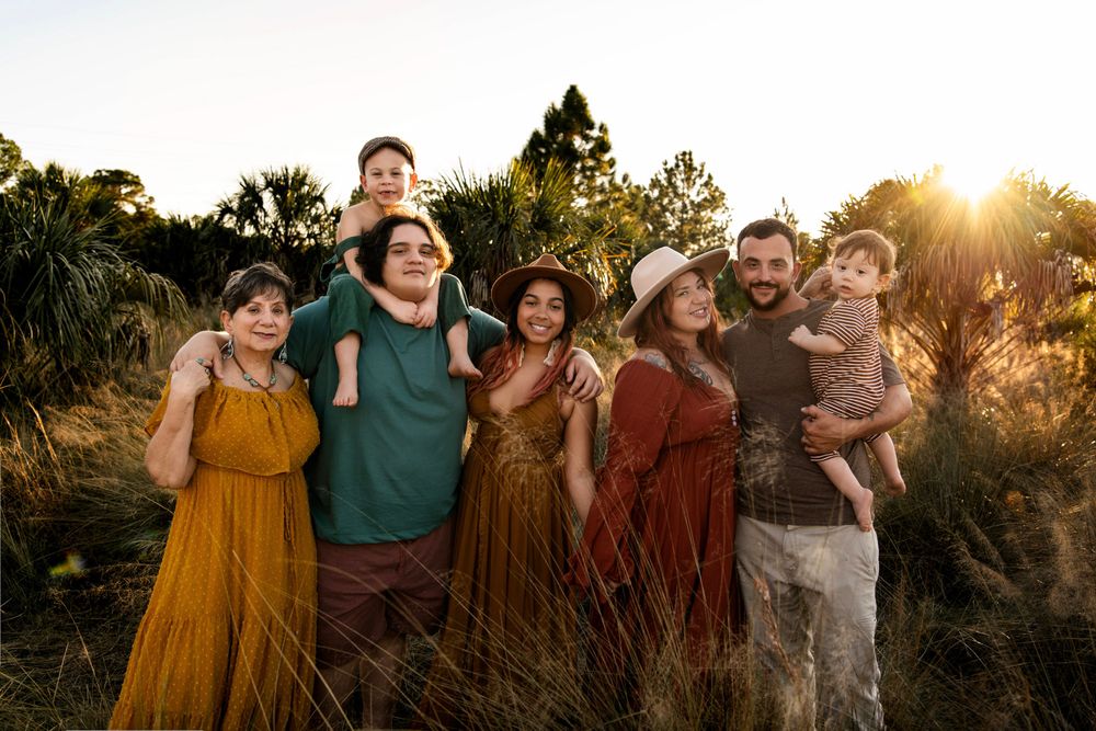 Extended family portrait at sunset in Tampa, Florida, featuring three generations together in a natural outdoor setting.