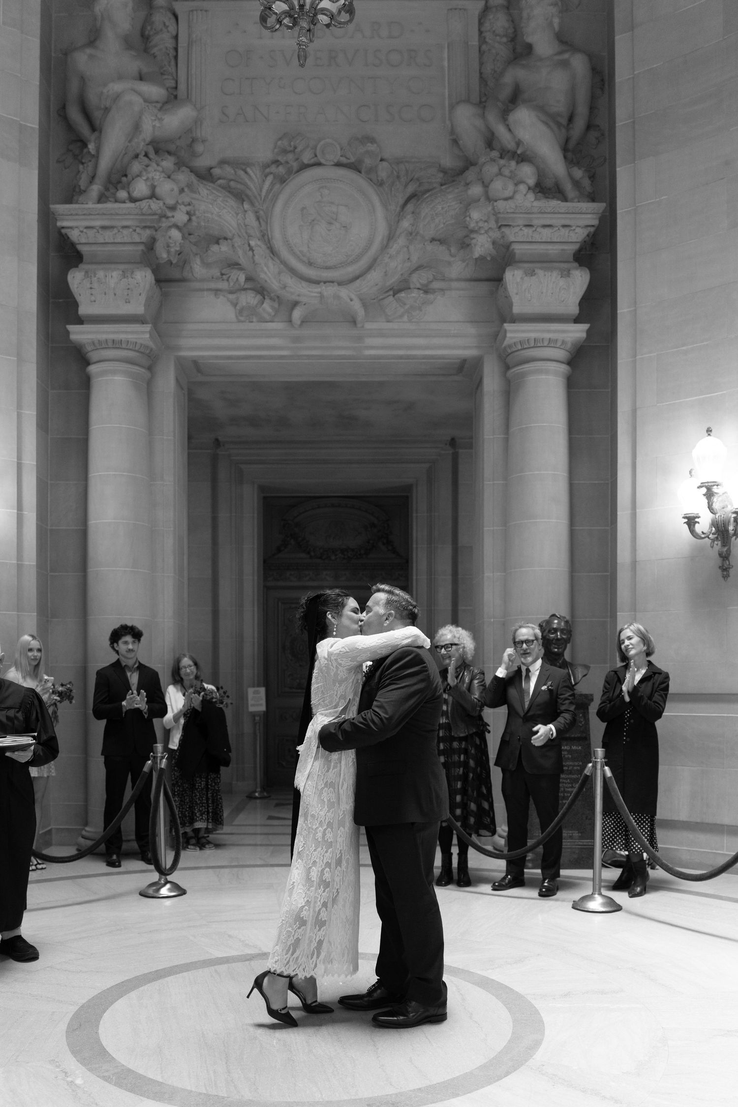 Black and white photo of a couple sharing their first kiss at a San Francisco City Hall wedding ceremony.