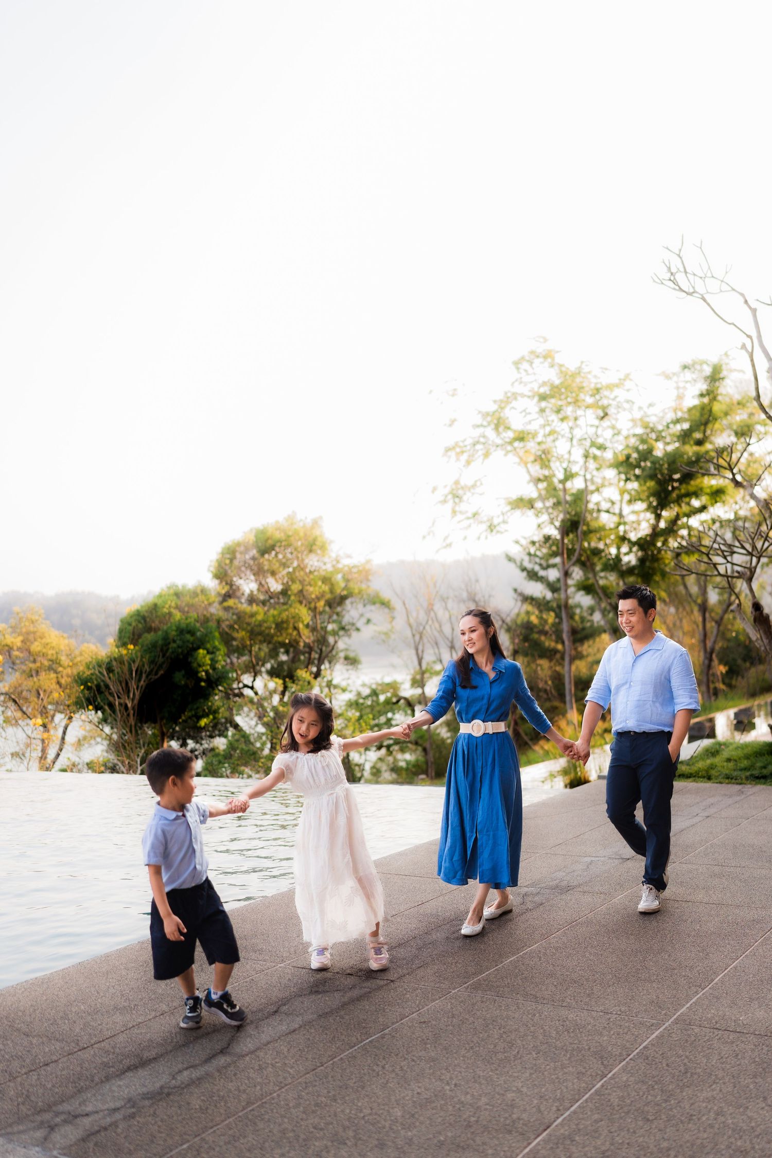 Happy Asian family with young daughter laughing together in a charming brick alleyway.