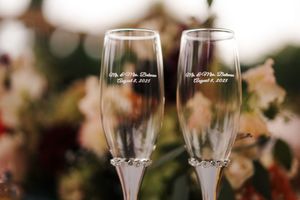 Two personalized engraved champagne flutes with wedding date inscription, crystal stem detail, elegant wedding toasting glasses.
