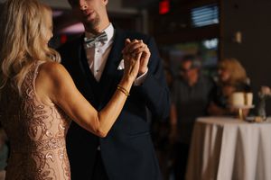 A mother and son share a tender first dance at a wedding reception, dressed in elegant formal attire.