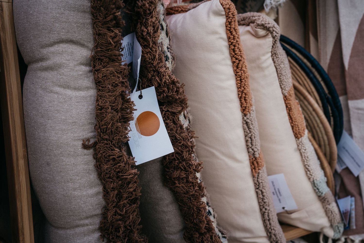 Neutral-toned textured cushions with price tags displayed at a market stall.