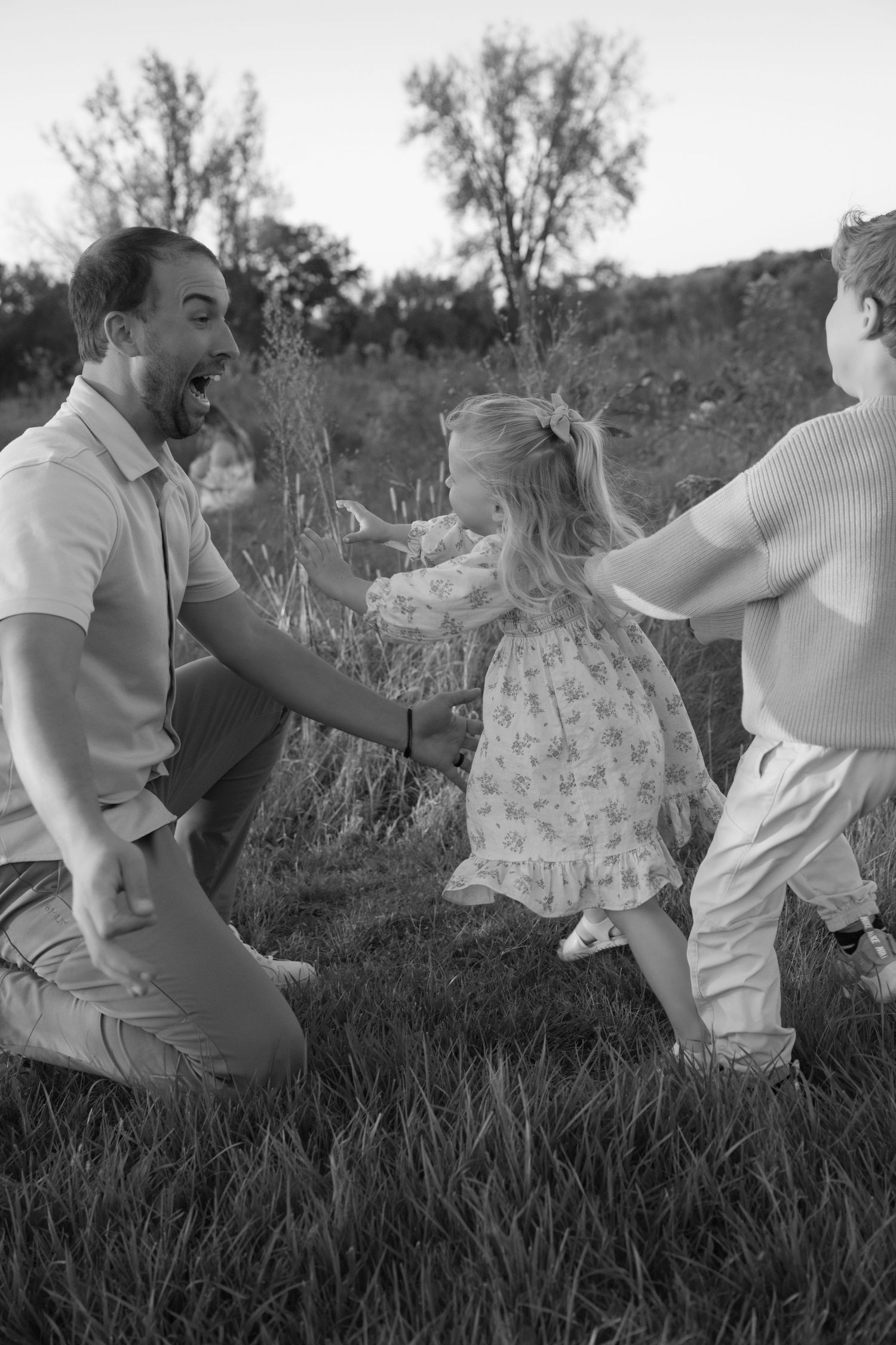 young brother and sister rush into dads arms while playing for a candid photo during a fall mini session in hudson wisconsin