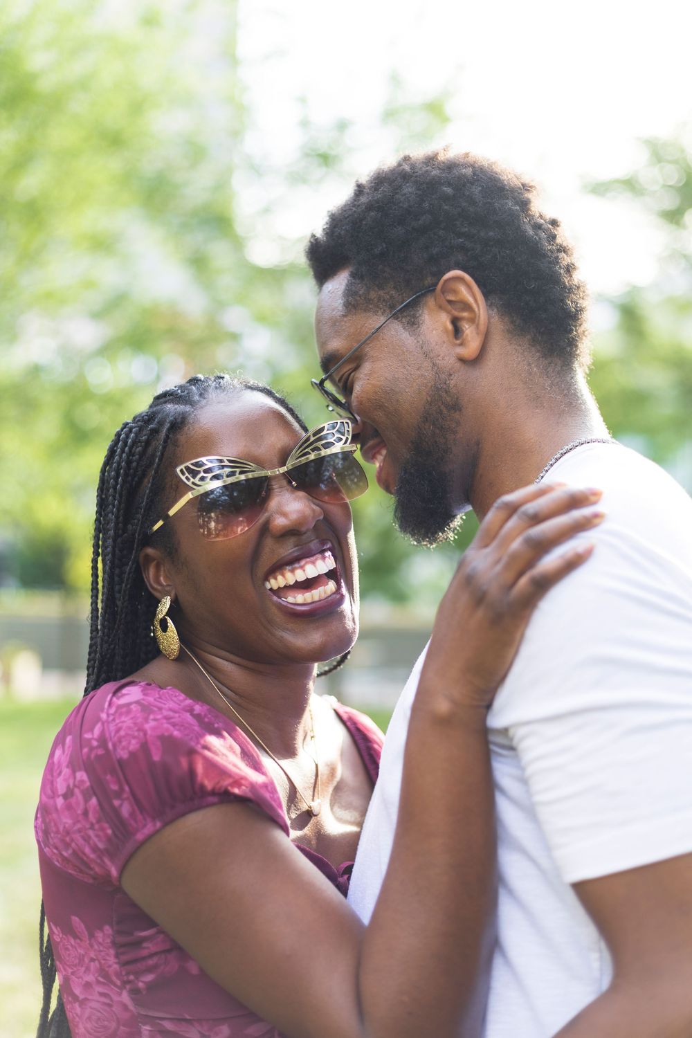 Fun couple laughing and embracing outdoors in a sunny park, couple session with Lexington wedding photographer.