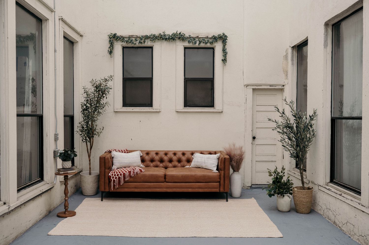 Brown tufted leather Chesterfield sofa surrounded by greenery in a minimalist studio in Bremerton Washington.