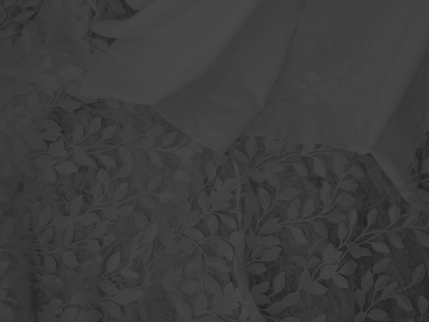Dark charcoal floral jacquard fabric with intricate leaf pattern texture, elegant black textile material close-up.