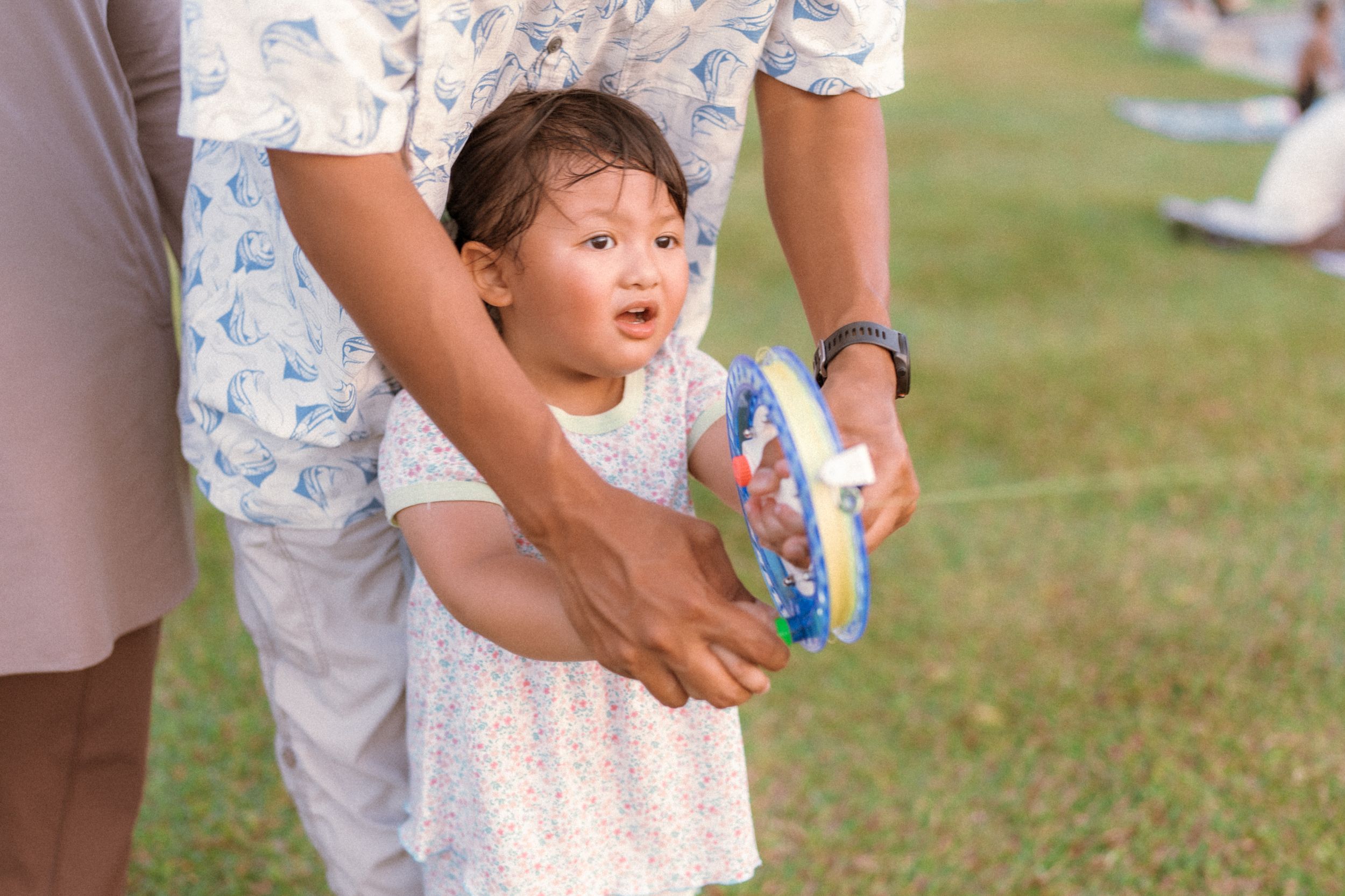 Child playing outdoors on grass with bubbles on a sunny day.