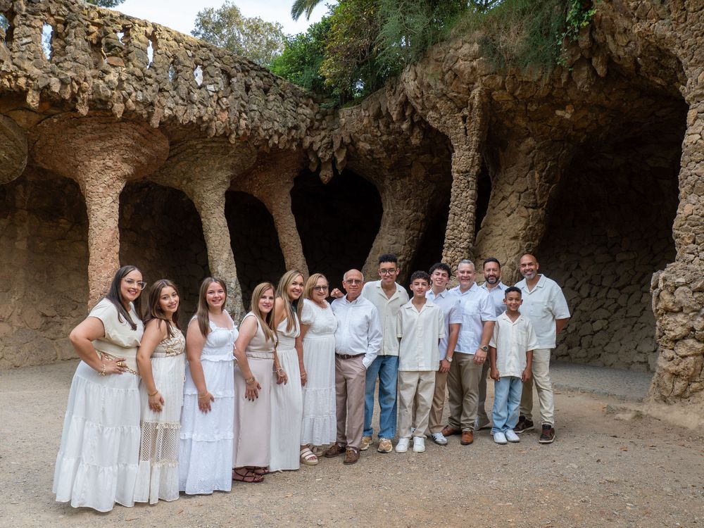 Group of people in white attire posing at Park Guell Barcelona stone archways.