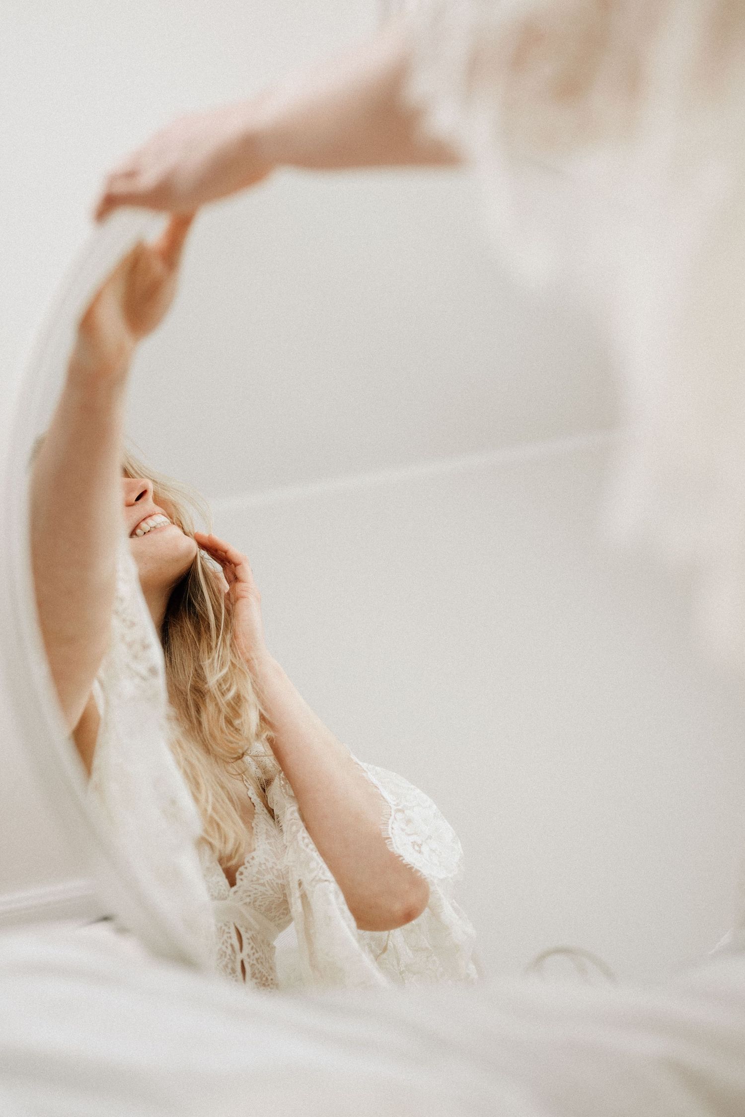 authentisch lächelnde Frau beim Boudoir Shooting im hellen, zarten Licht in einen Spiegel fotografiert