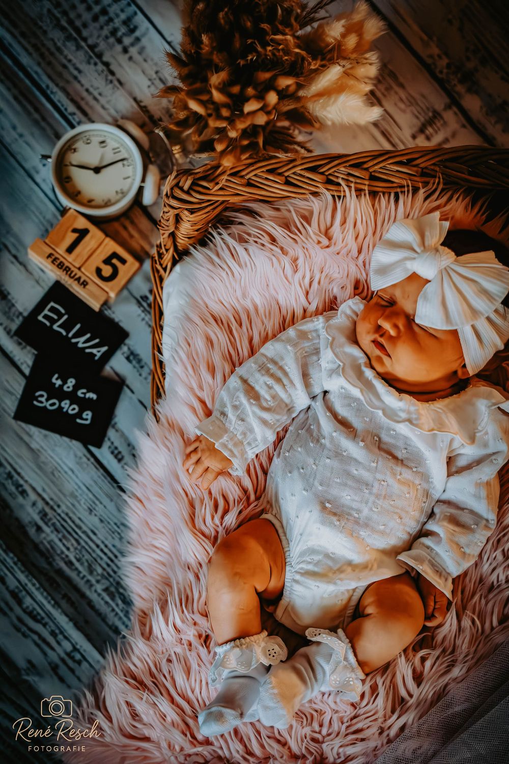 Newborn baby Elua lying in a wicker basket on pink fur, born February 15, weighing 3090g and measuring 48cm.