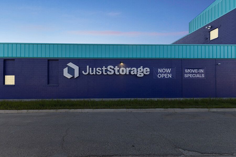 JustStorage building sign advertising now open with move-in specials at dusk.