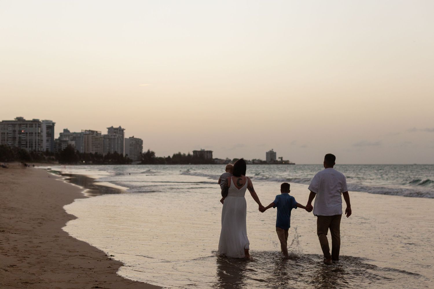Family portrait on the beach in Isla Verde, Carolina, Puerto Rico. Father, mother and two sons. Sunset silhouette.