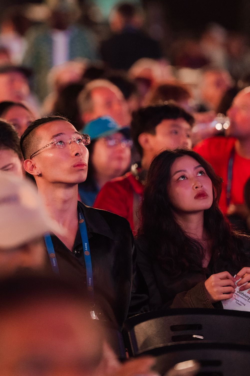 Diverse audience members attentively watching a presentation at a Rotary International conference event.