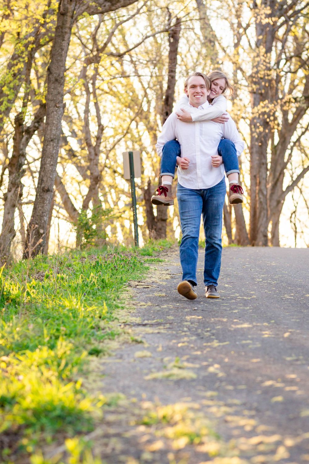 Couple walking hand in hand along a tree-lined path near the Buffalo River during an outdoor couples session