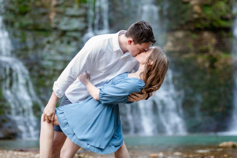 Couple in a romantic dip and kiss in front of Triple Falls waterfall during a couples session in Jasper, Arkansas