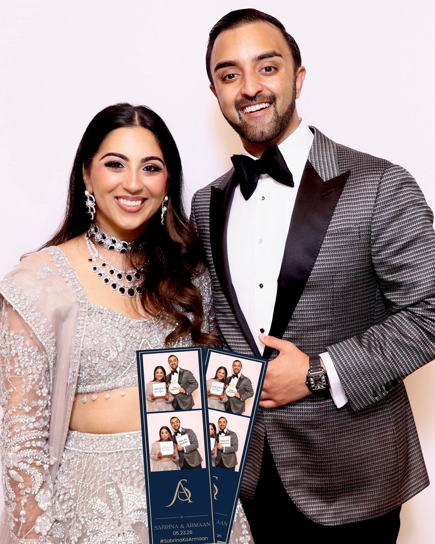 Couple in formal attire holding photo booth strips at an elegant celebration event.