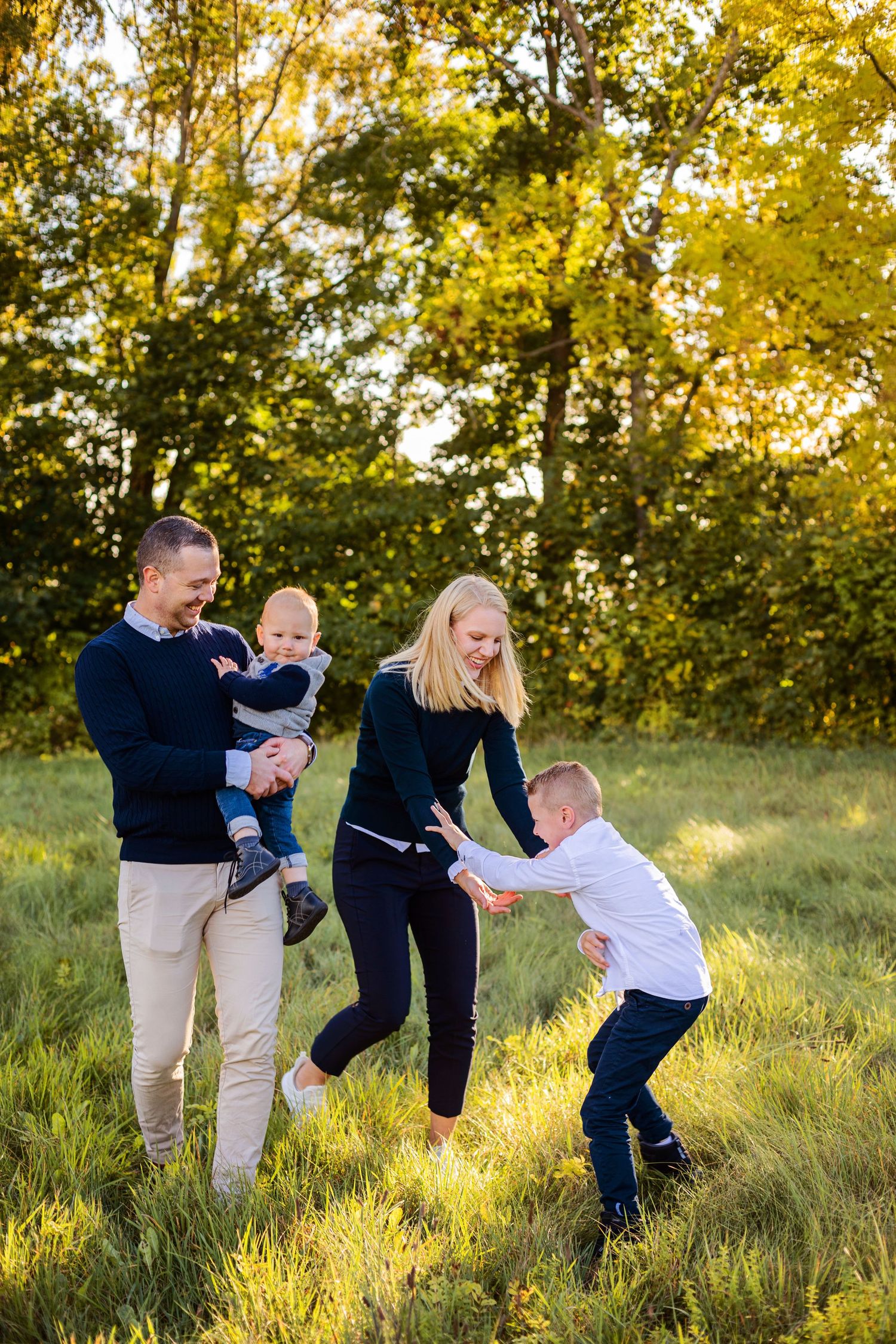 Family enjoying a sunny afternoon together in a grassy meadow surrounded by trees.