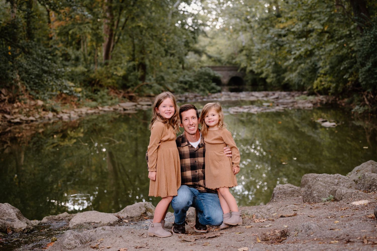 A father with his two young daughters for photos, surrounded by lush green trees. Sharon Woods Cincinnati