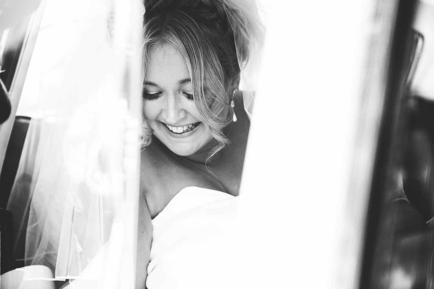 Black and white photo of a smiling bride in a veil, radiating joy on her wedding day. London and Kent wedding photographer