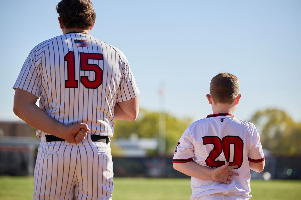 Two baseball players wearing jerseys numbered 15 and 20 stand side by side on a field.