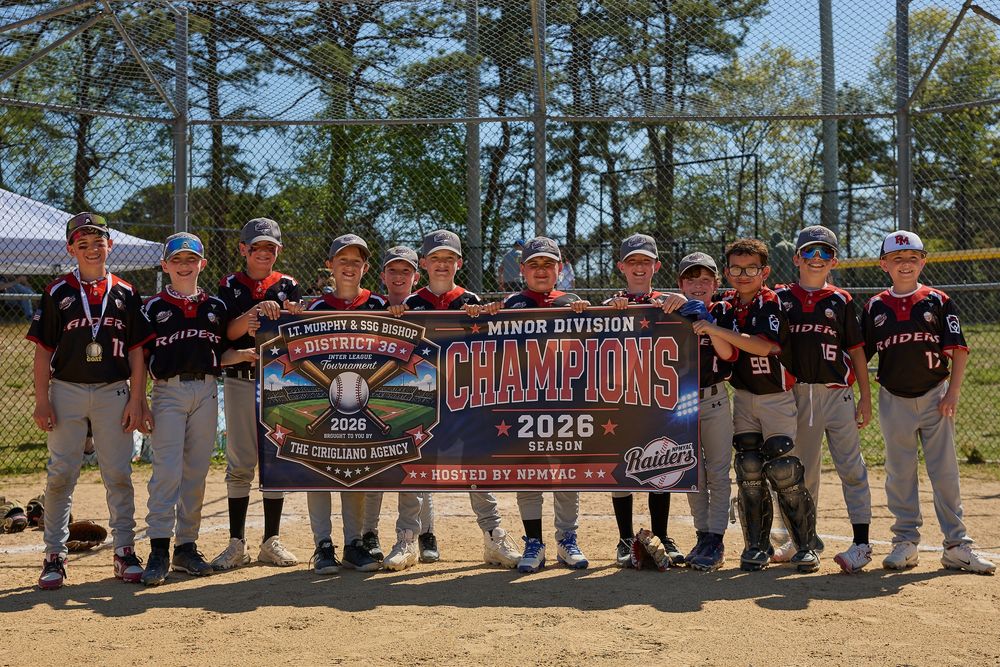 Youth baseball team poses with Minor Division Champions 2026 banner outdoors on a sunny day.