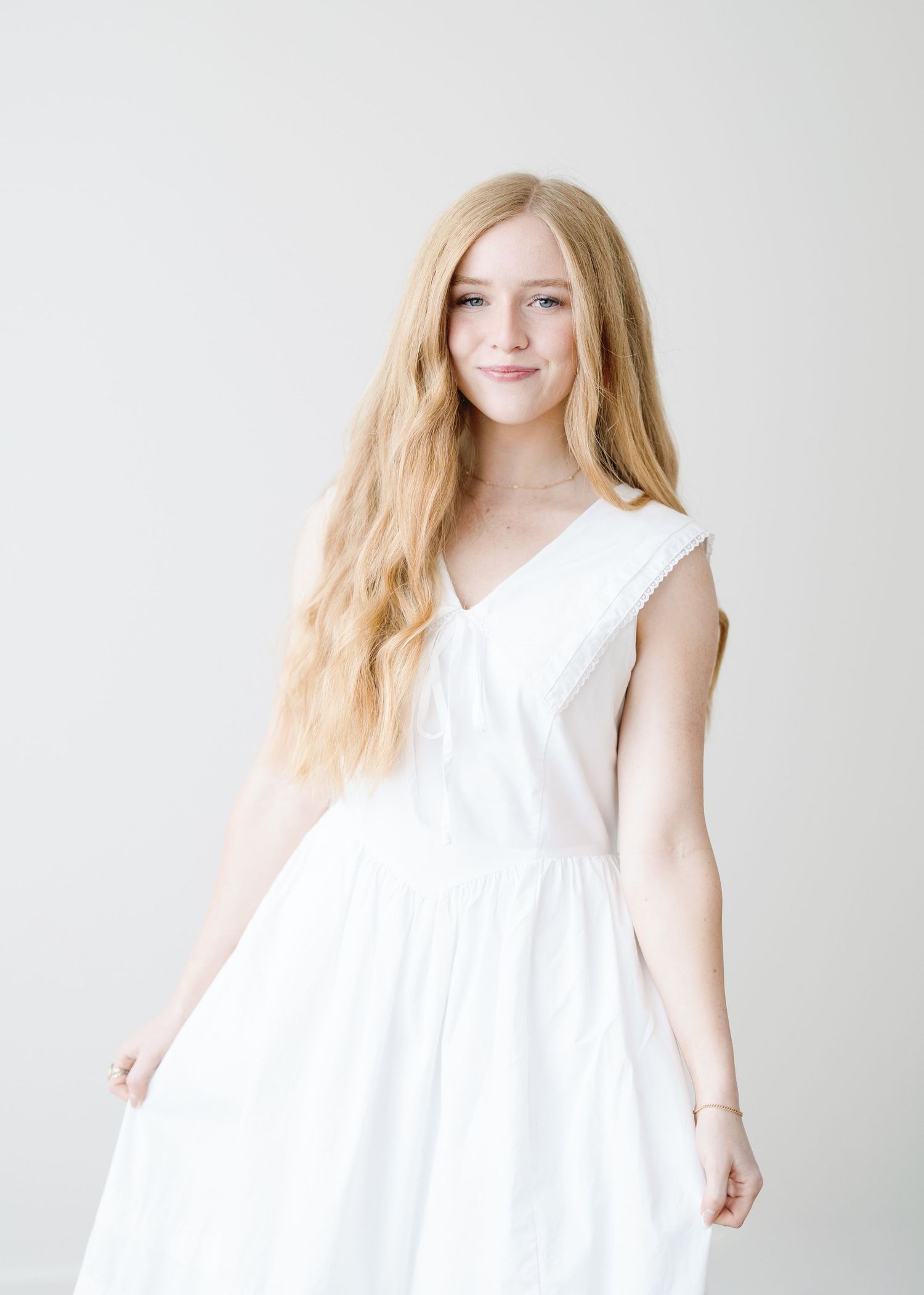 Black and white portrait of a photographer sitting on steps with professional camera equipment and wearing a polka dot dress.