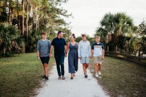 A group of people walking together on a path surrounded by palm trees and lush greenery in a tropical setting.