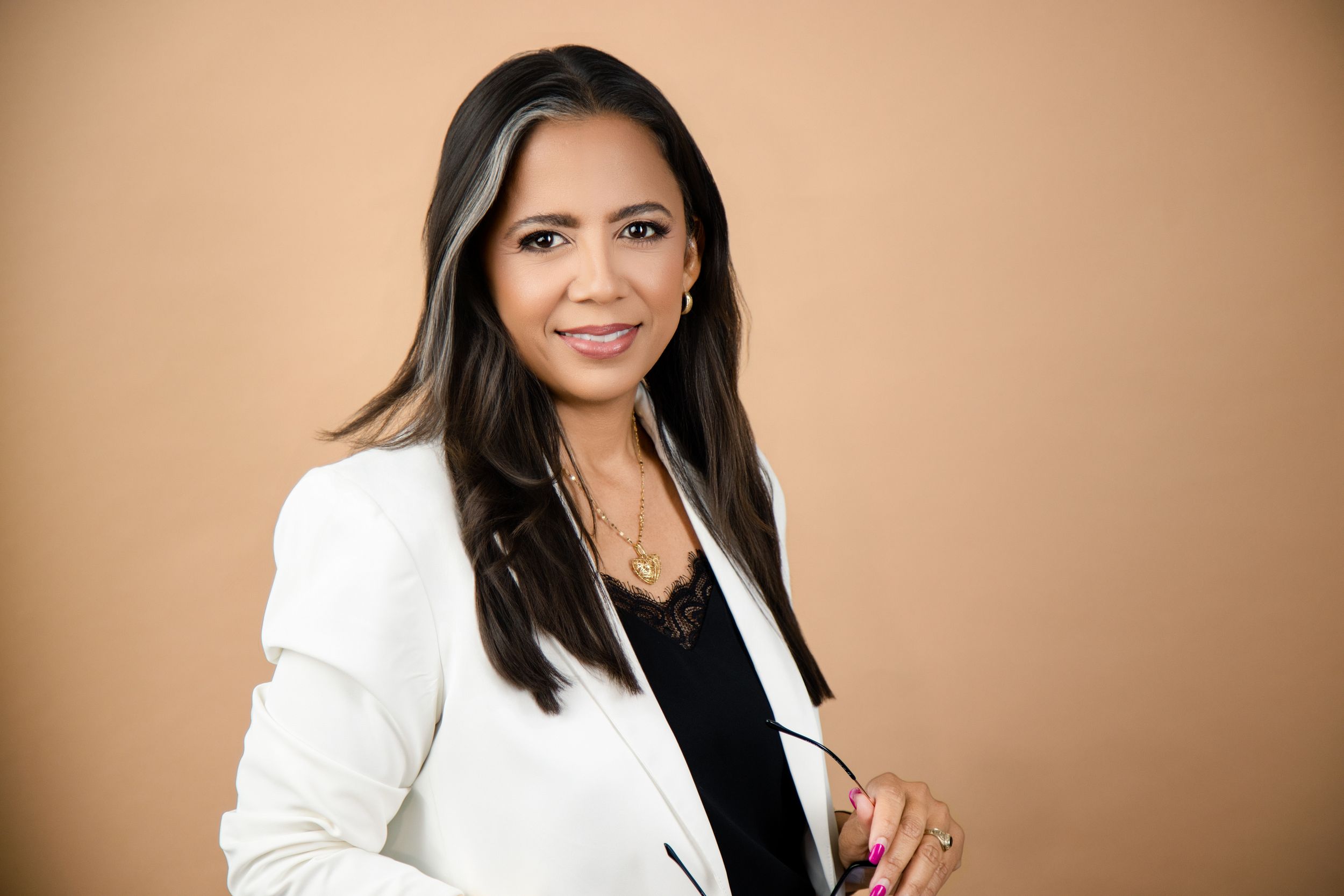 Professional outfit featuring a pink sleeveless vest layered over a white long-sleeve top and black skirt, styled for work.