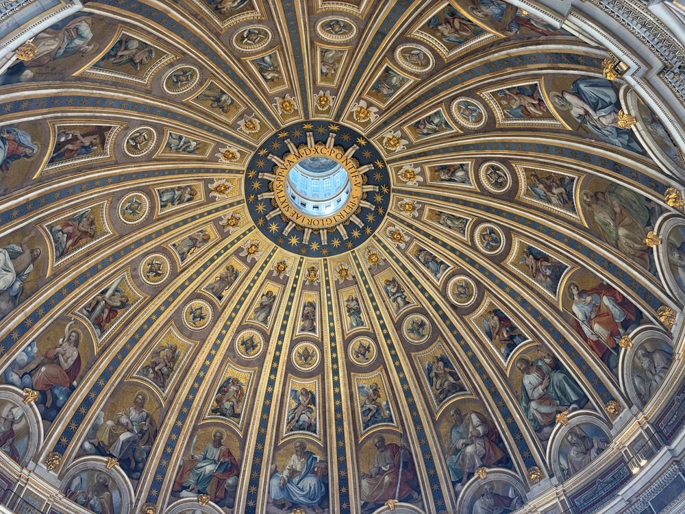 Ornate Renaissance dome interior with radiating gilded ribs, mosaic panels of saints and a central oculus glowing with soft blue light.