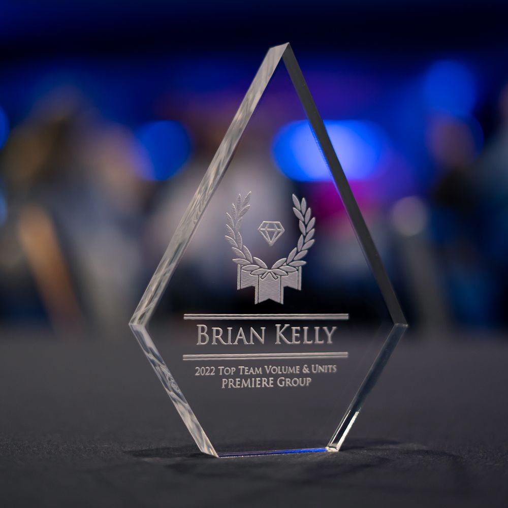 Crystal diamond-shaped award engraved with Brian Kelly 2022 Top Team Volume & Units Premiere Group achievement recognition.