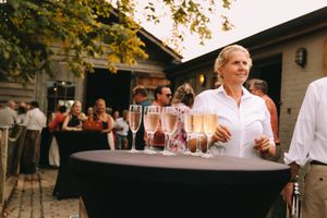 Gasten genieten van champagne tijdens een zomerse trouwreceptie in Deinze