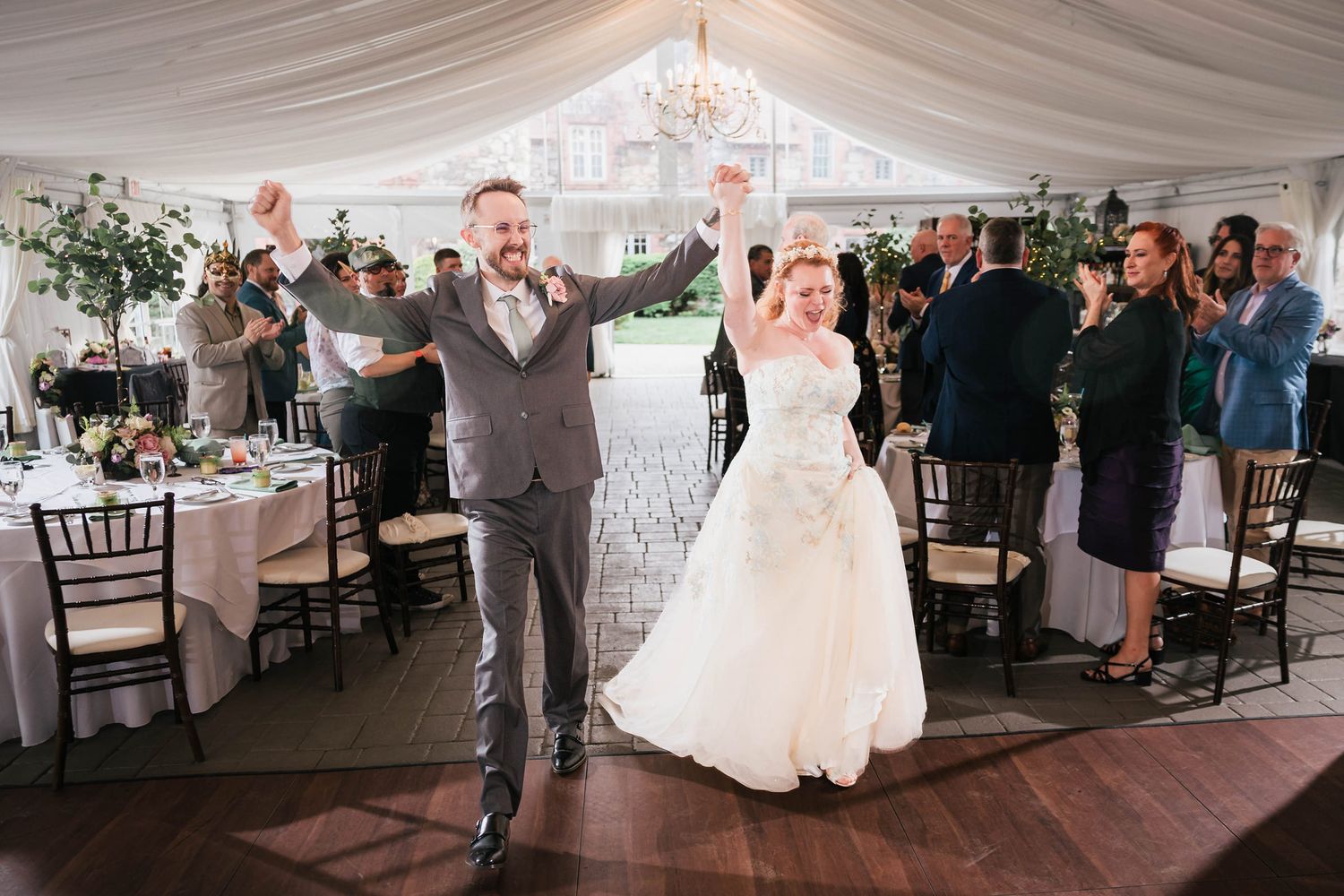 Full wedding party lined up on the dance floor, cheering and applauding as the newlyweds are announced.